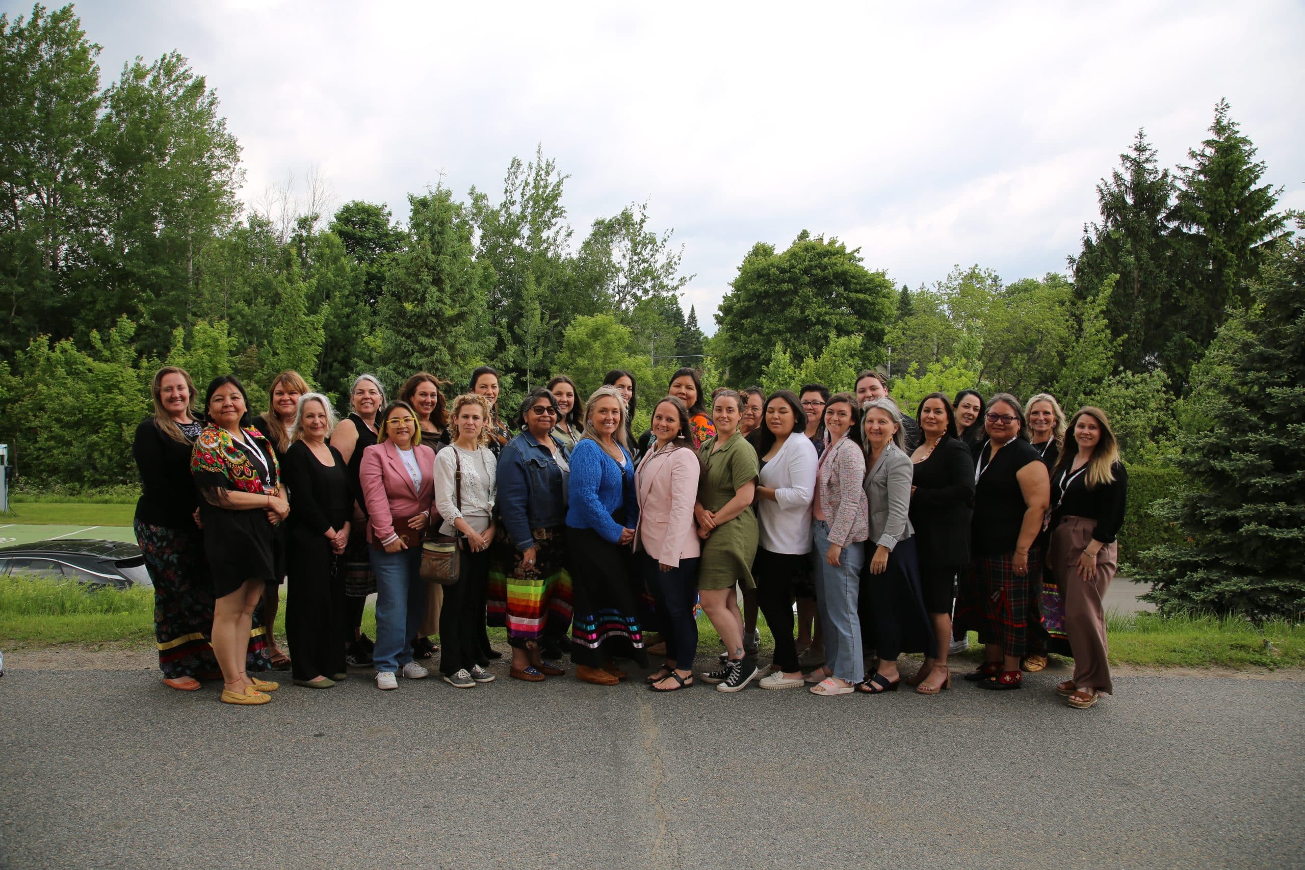 336A0537 Participants of the Women's Leadership program gathered outdoors, surrounded by greenery.
